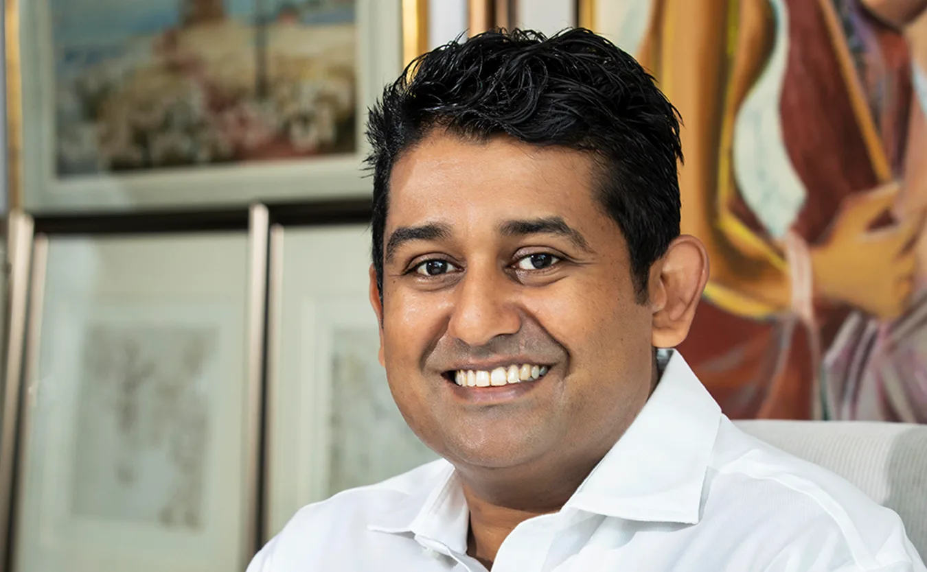 Malaka Talwatte, seated before framed works from his collection.