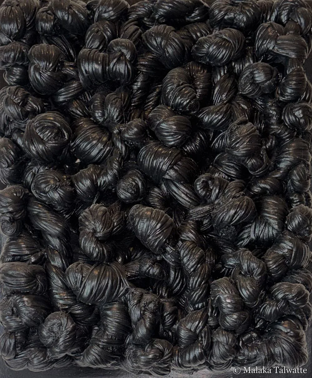 A dense relief of black knotted and twisted material, a work by Mahen Perera.