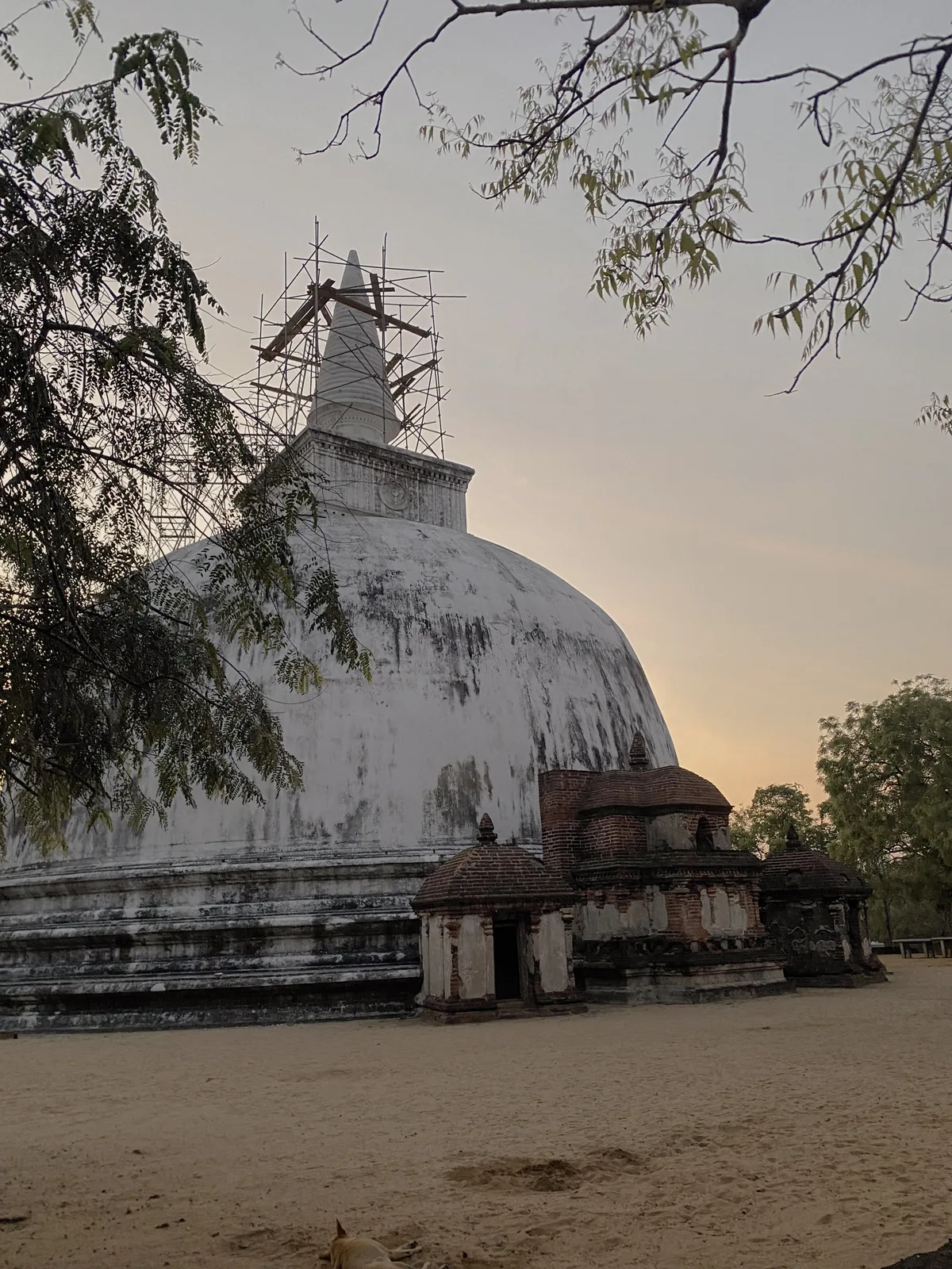 Kiri Vehera at Polonnaruwa, a white-plastered bubble-domed stupa with small brick shrines at its base, at dusk.