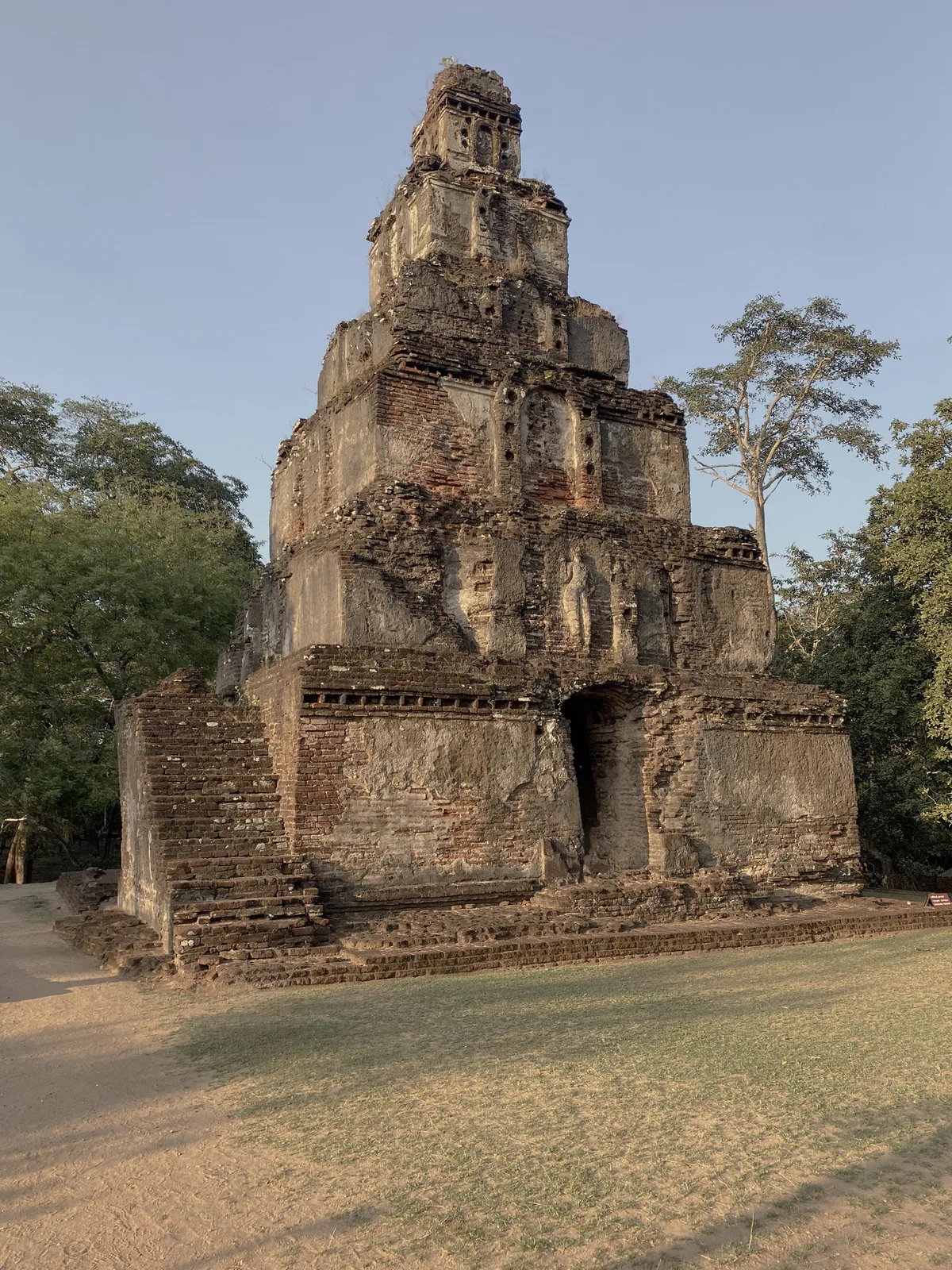 The Sat Mahal Prasada at Polonnaruwa, a stepped brick pyramid tower of receding tiers, moss-grown.