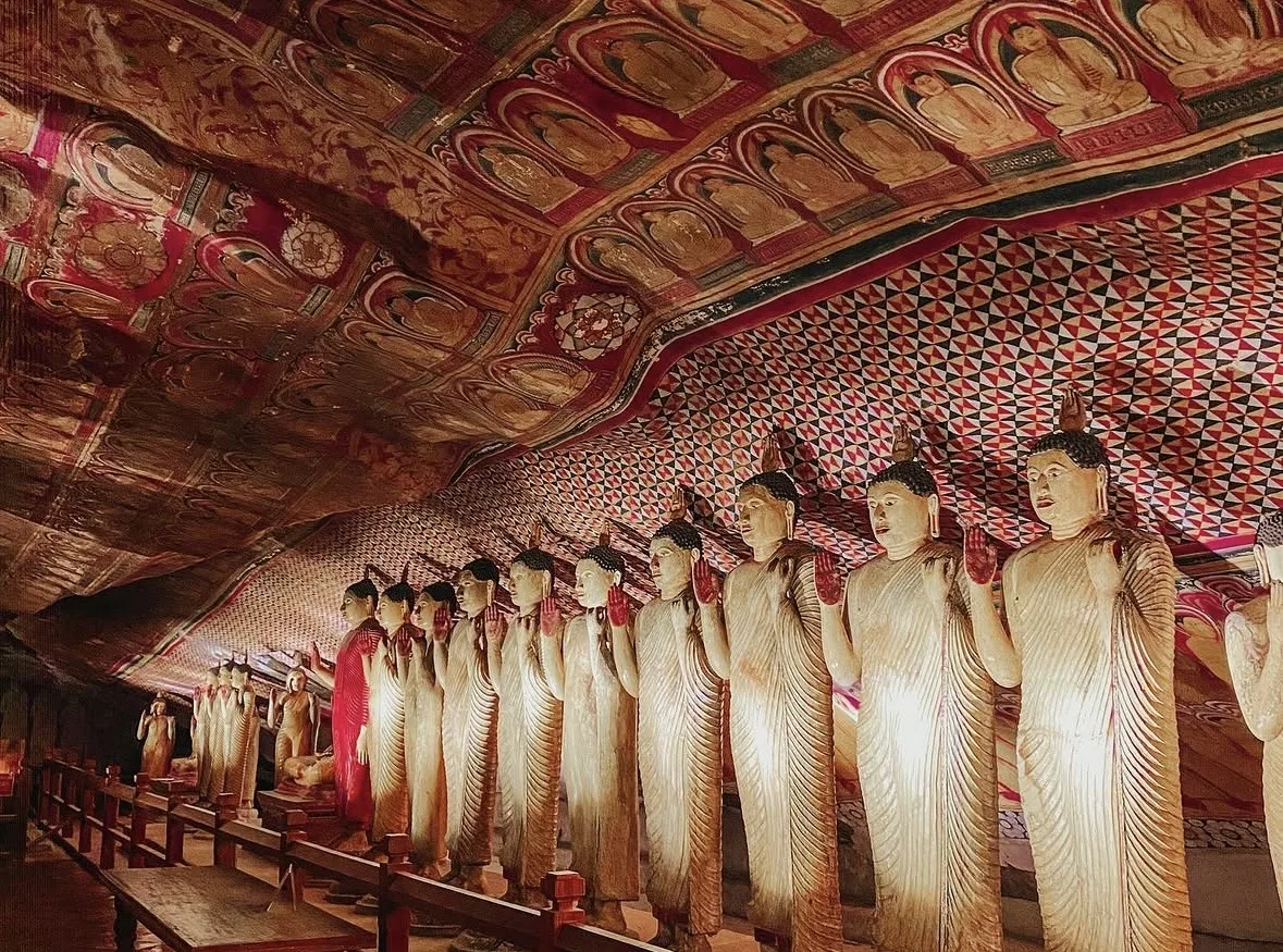 The rock interior at Dambulla: gilded Buddha images ranked along the living rock beneath a densely painted ceiling.