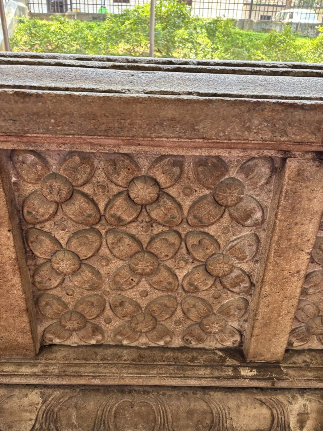 A carved stone panel of lotus rosettes in a grid, at the Temple of the Tooth.