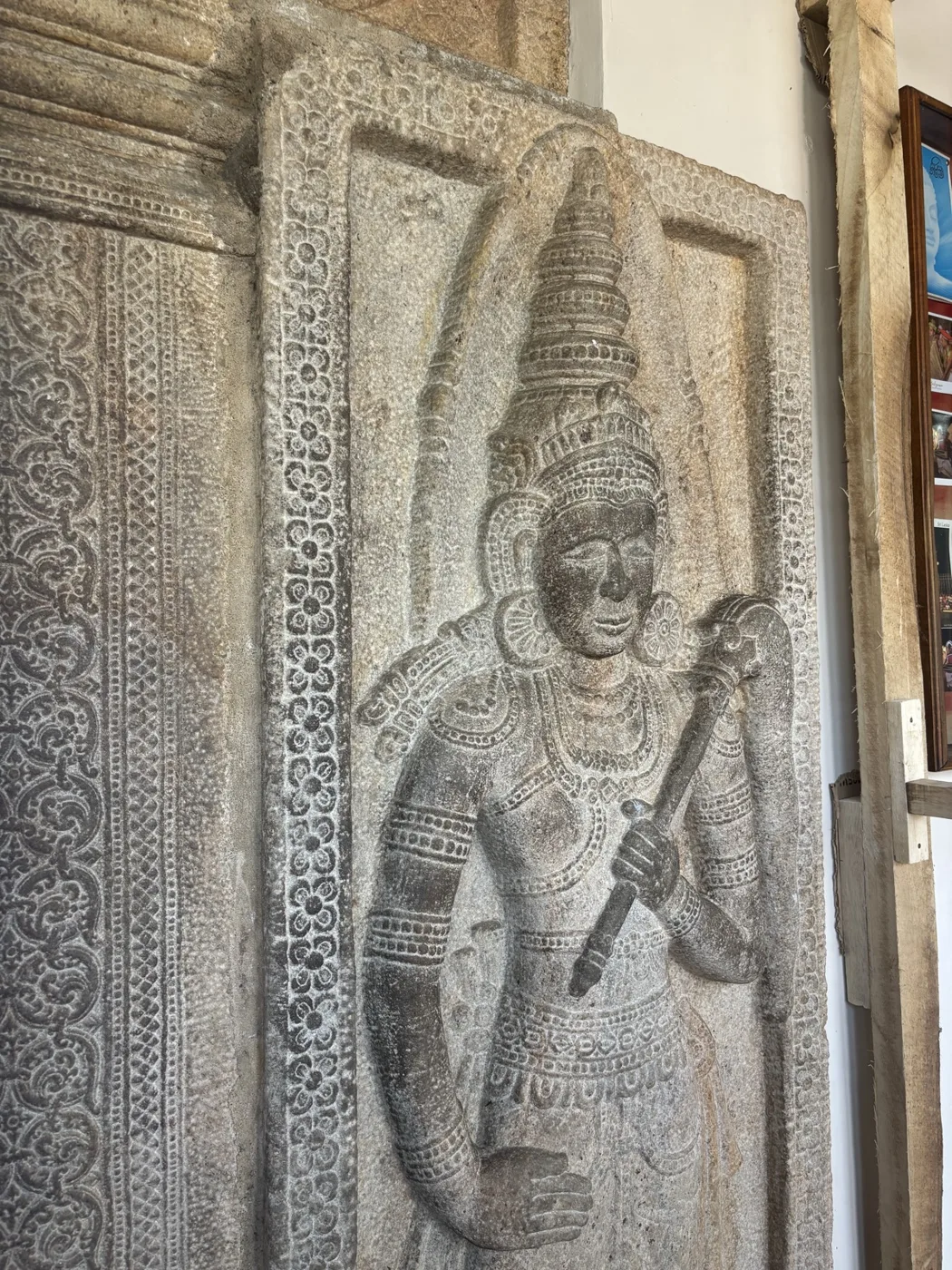 A carved stone door-guardian, a Doratu Pala, an armed jewelled figure in low relief.