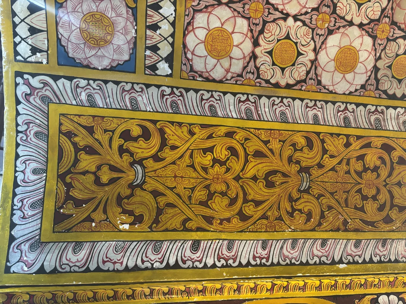 A painted Kandyan panel: lotus rosettes above a band of gold scrolling creeper.