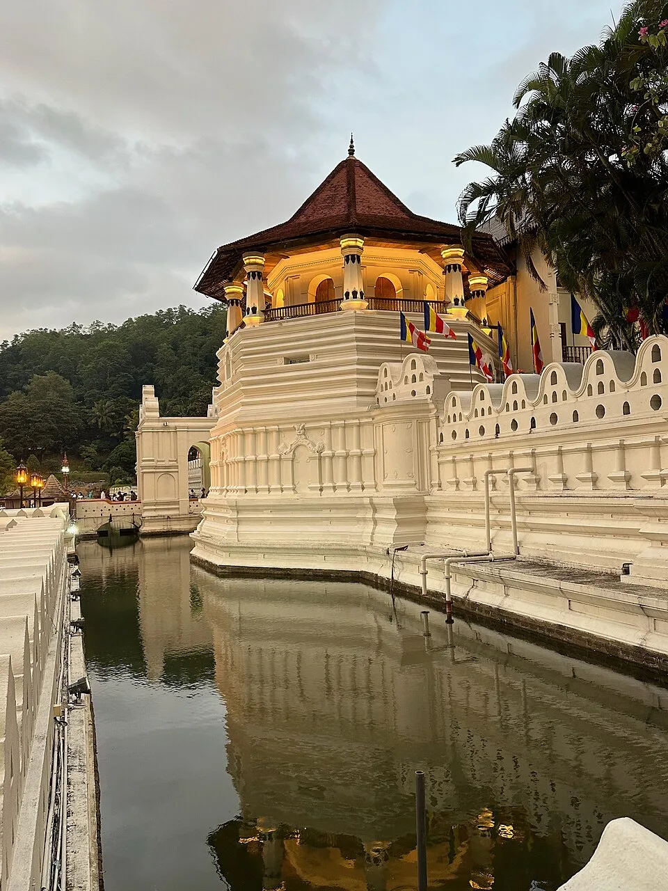 The octagonal Pattirippuwa tower rising above the wall of the Temple of the Tooth at Kandy, reflected in the moat.