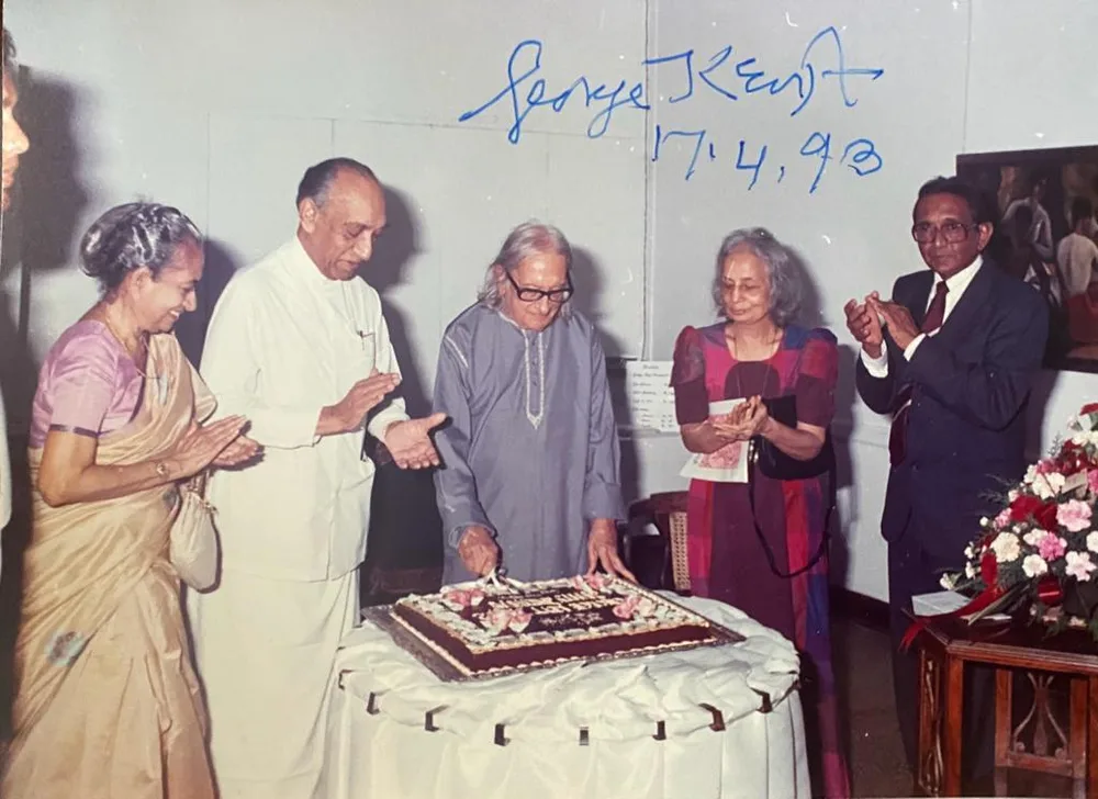 George Keyt cutting his 90th birthday cake, with guests.